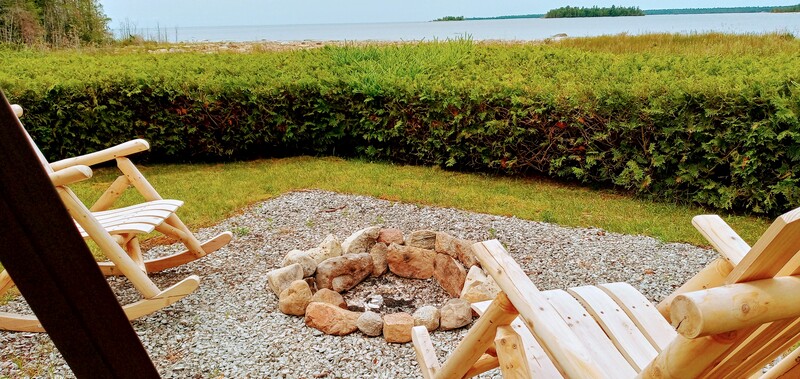 Up close photo of the new stone fire ring nestled with a pair of wood rockers and the huge swing.